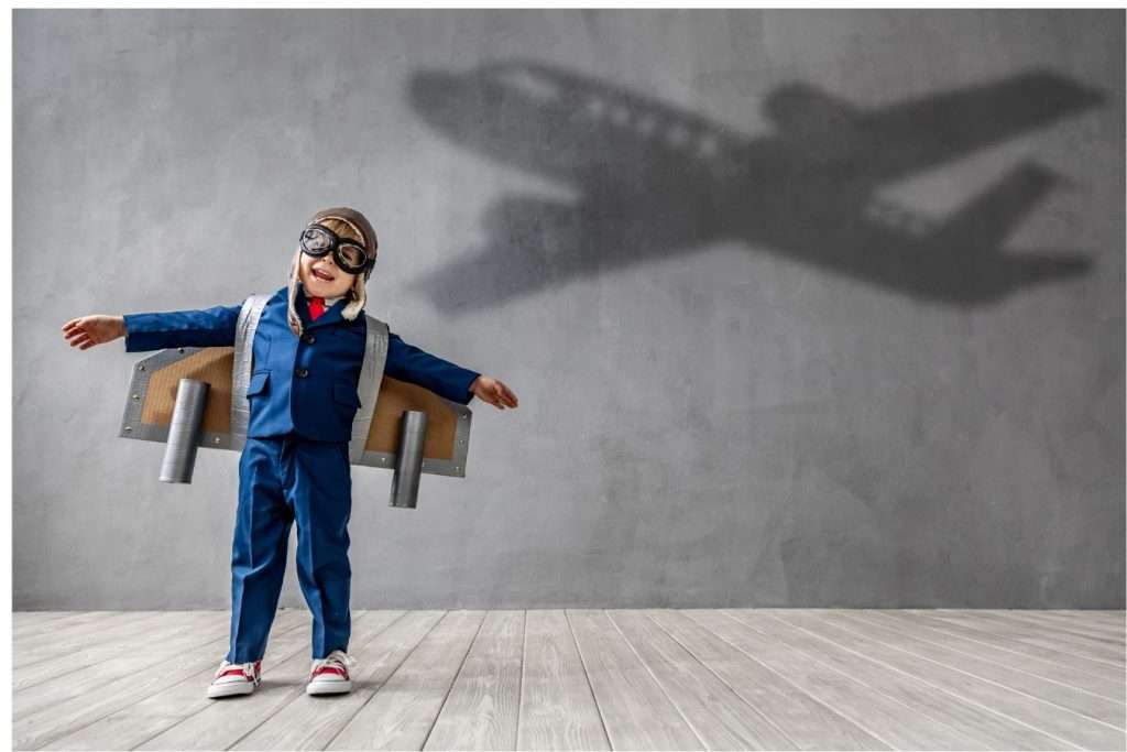 Child dressed as a pilot with aeroplane shadow in background. Dreams